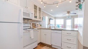 A modern kitchen with white cabinetry, a built-in oven, a dishwasher, and a ceiling fan.