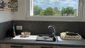 A kitchen with a window, a sink, and a dish rack.