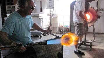 A workshop with two individuals working on a glassblowing project.