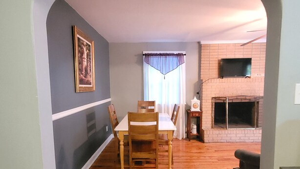 A dining area with a wooden table and chairs, a fireplace, and a television mounted on the wall. - Spacious 2 Bedroom Home within 8 Minute walk to Downtown Augusta (Augusta)