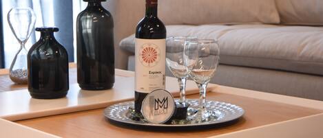 Una botella de vino, dos copas y botellas decorativas sobre una bandeja en una habitación con un sofá.