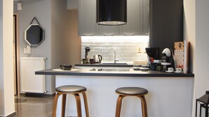 Cozinha moderna com ilha central, dois banquetes, máquina de café e geladeira.