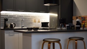 Cozinha moderna com ilha central, eletrodomésticos de aço inoxidável e banquetas de madeira.