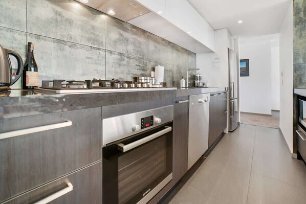 A modern kitchen with a built-in oven, stainless steel appliances, and a large countertop.