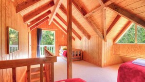Una cabaña de madera con habitación en el altillo, un balcón y vistas al exterior.