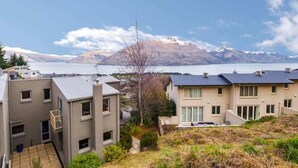 Un quartier résidentiel avec des maisons modernes, un ciel dégagé et une chaîne de montagnes en arrière-plan.