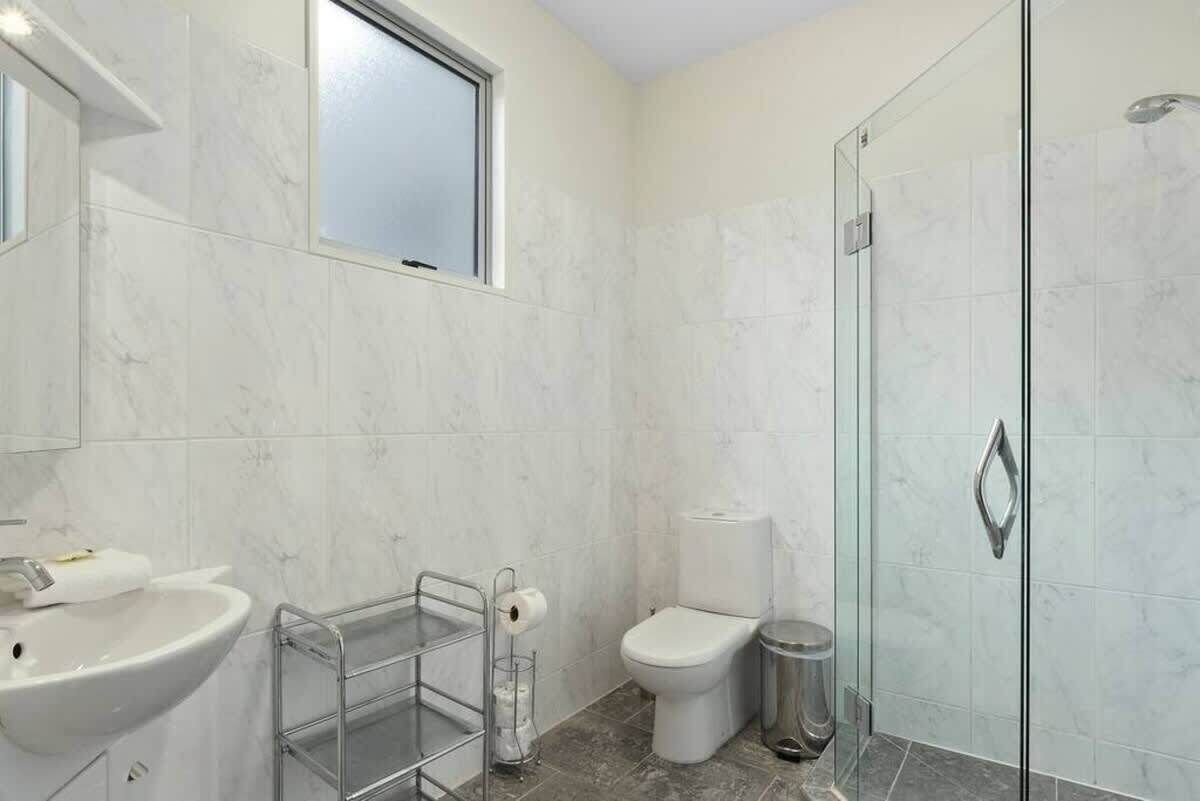 Une salle de bain moderne avec une douche à parois de verre, un lavabo blanc et des toilettes.