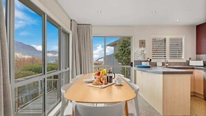 Une cuisine moderne avec un coin repas, de grandes fenêtres et une vue sur les montagnes.