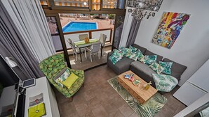 Un balcon avec une piscine, un ensemble de canapés, une table à manger et un téléviseur.