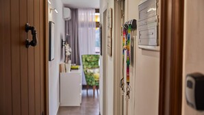 Un couloir avec des portes en bois, un porte-manteau avec des clés, et une petite table avec une chaise à l’arrière-plan.