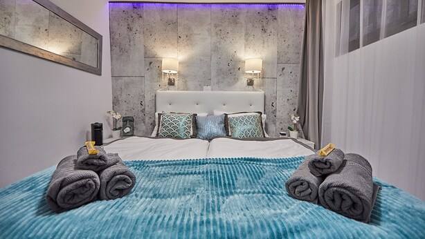 Une chambre d’hôtel moderne avec un grand lit, deux lampes fixées au mur et un mur à texture.