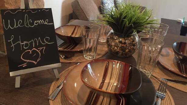 A dining table set with plates, cutlery, and a sign that reads "Welcome Home".
