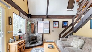 A cozy living room with a fireplace, a sofa, a coffee table, and a staircase. - River Front Cabin in Plain, close to Lake Wenatchee

Short term rental #000168 (Leavenworth)