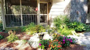Stroll through the beautifully landscaped garden, featuring a variety of plants and flowers, and a serene stone feature.