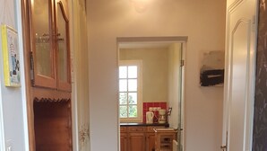 Un couloir avec des armoires en bois, un sol carrelé et, au fond, un espace cuisine.