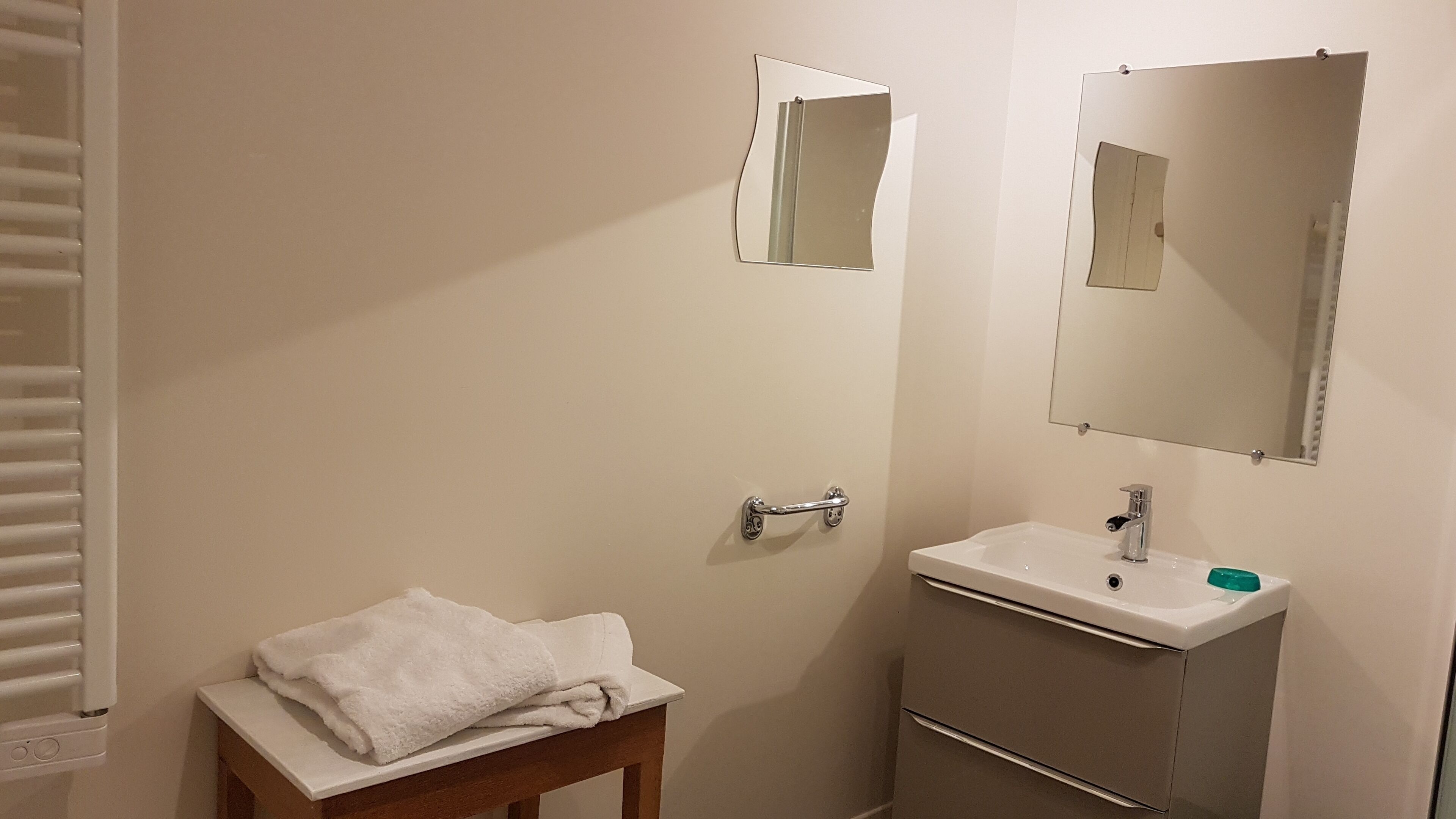 Une salle de bain équipée d’un lavabo, d’un miroir, d’un porte-serviettes et d’un radiateur.