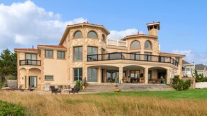 Une grande maison à étages, dotée d’une façade en pierre, de nombreux balcons et d’un vaste porche à l’avant.