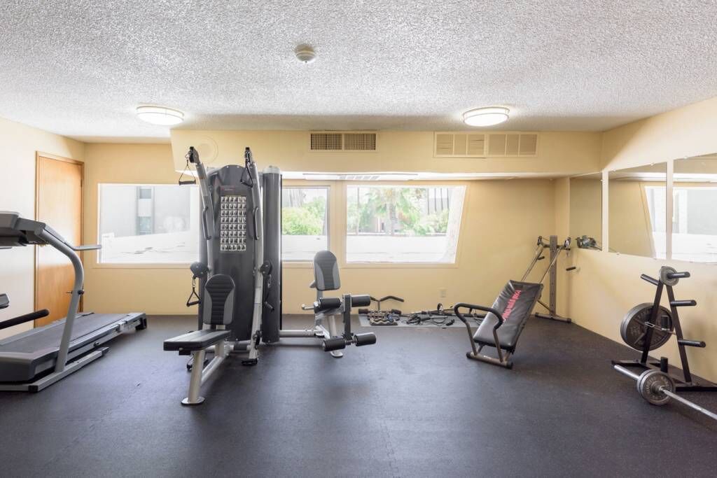 A gym with a treadmill, weight machines, and a bench.