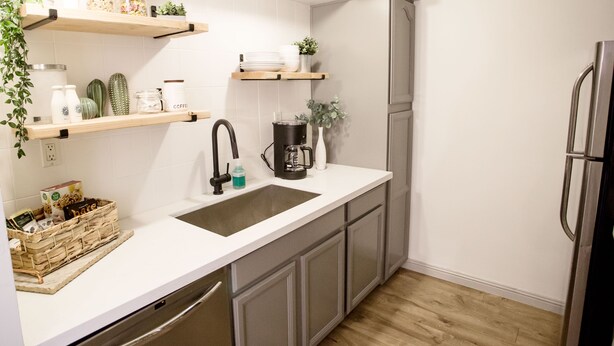 A modern kitchen with white cabinetry, a stainless steel refrigerator, a coffee maker, and various kitchen utensils on open shelves. - Desert Modern Old Town Oasis | Fresh Renovation! | Walk to Restaurants & Bars (Scottsdale)