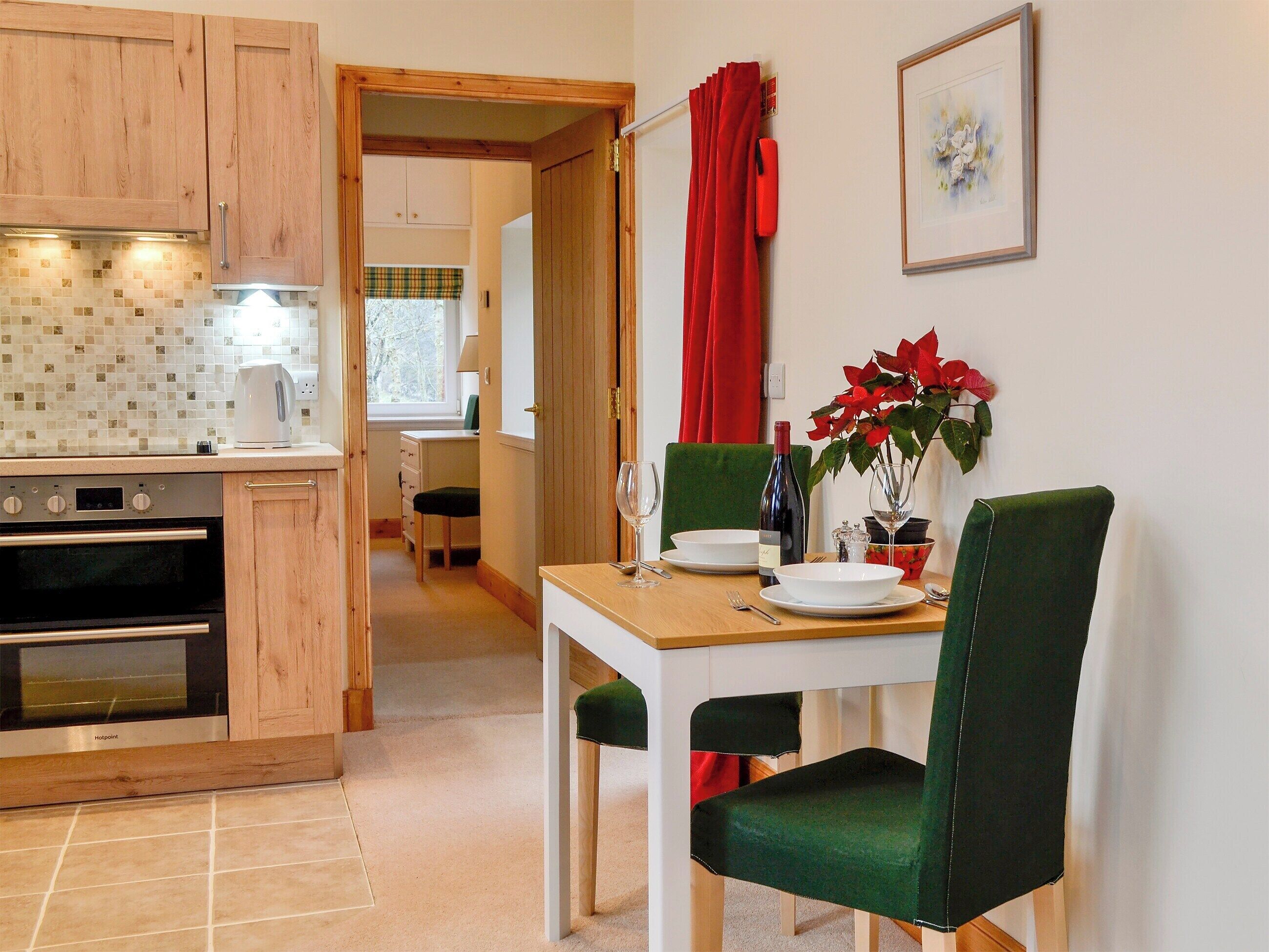 A modern kitchen with wooden cabinets, a built-in oven, and a dining area with a table set for two.