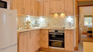 A compact kitchen with wooden cabinets, a built-in oven, and a microwave. - The Old Inverchroskie Kennels (Enochdhu, near Pitlochry)