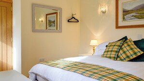 A hotel room with a bed, a bedside table with a lamp, a framed picture on the wall, and a wooden door. - The Old Inverchroskie Kennels (Enochdhu, near Pitlochry)