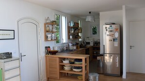 Eine moderne Küche mit Holzausstattung, einem Edelstahlkühlschrank und einem eingebauten Backofen.