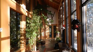 A spacious hallway with large windows, a potted plant, a bench, and a small table.
