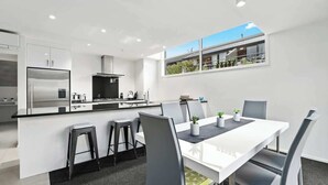 A modern kitchen with a central island, bar stools, and a dining table with chairs.
