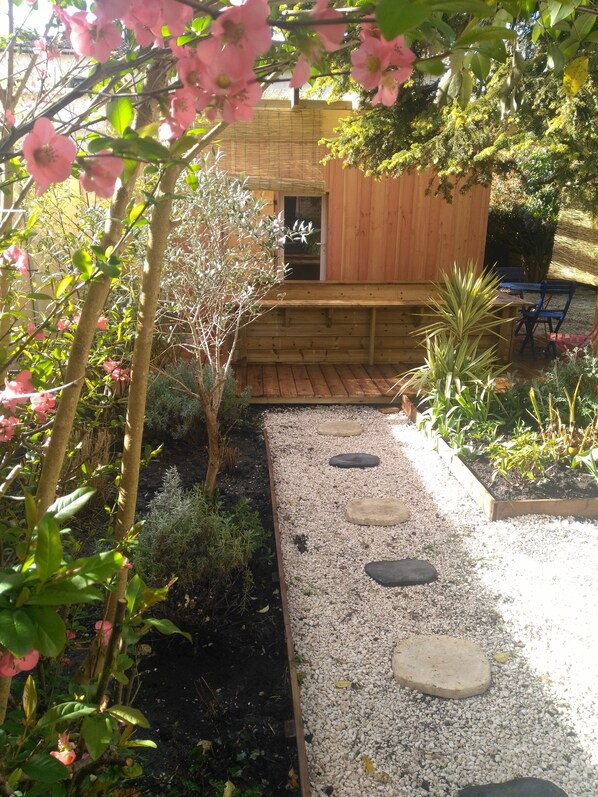Stroll along the winding gravel path to a serene garden oasis, featuring a peaceful bench and lush greenery.