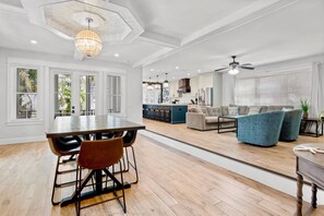 A spacious living area with a dining table, sofas, and a kitchen in the background. - Pool, Putting Green, Steps to Shopping, Tons of Living Space -The Shore House (Lido Key)
