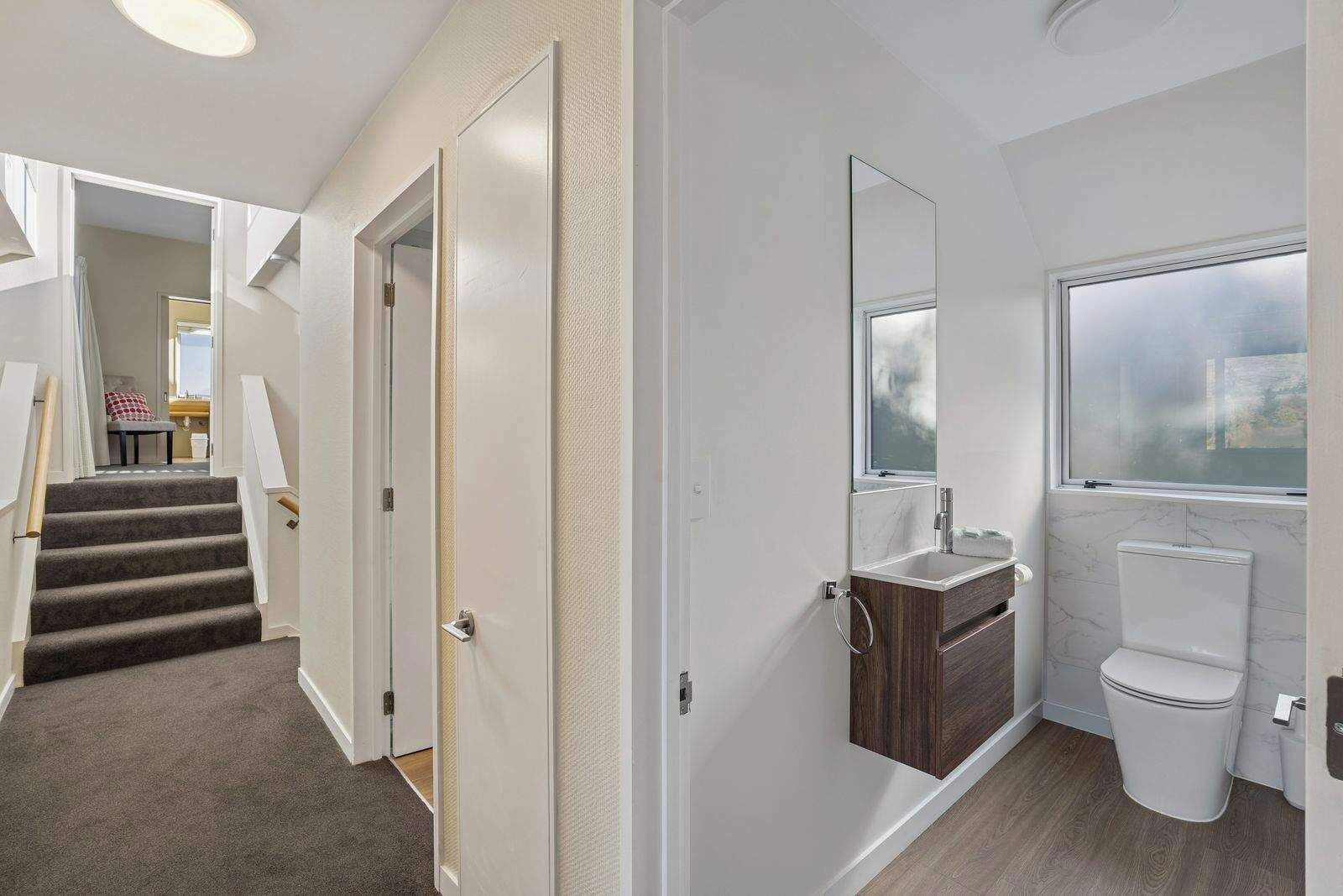 A modern bathroom with a toilet, sink, and window.