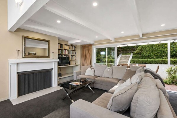 A modern living room with a fireplace, sofa, coffee table, and bookshelves.