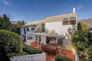 Ein modernes Haus mit Terrasse, Essbereich und Bergblick.