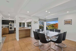 A modern kitchen with a dining area, large windows, and a view of a lake.