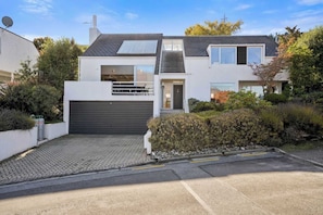 Et moderne hus med to etager, garage, solpaneler og indkørsel.