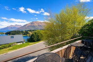 Un balcon avec coin salon extérieur donnant sur un lac et des montagnes.