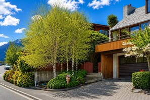 Une maison moderne dotée d’une terrasse en bois, d’un garage et offrant une vue sur les montagnes.