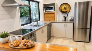 A modern kitchen with a stainless steel refrigerator, a microwave, and a large window.