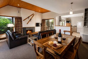 Un salon moderne avec une cheminée, une table à manger avec des verres à vin et un coin cuisine.
