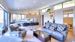 A modern living room with a grey sofa set, a coffee table, and a dining area with chairs.