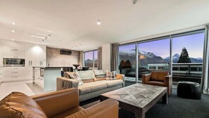 A modern living room with a sofa, coffee table, and a view of mountains through large windows.