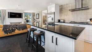 A modern kitchen with a central island, stainless steel appliances, and a large window overlooking a garden.