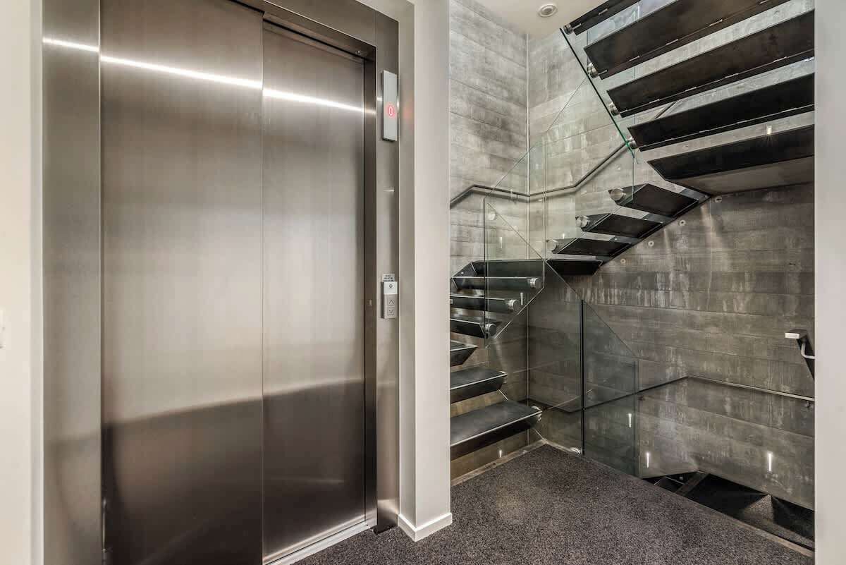 A modern elevator and a glass-walled staircase in a commercial building.