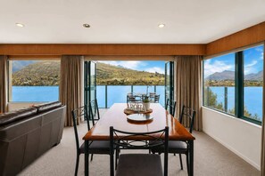 A dining area with a table and chairs, a sofa, and large windows with a scenic view.