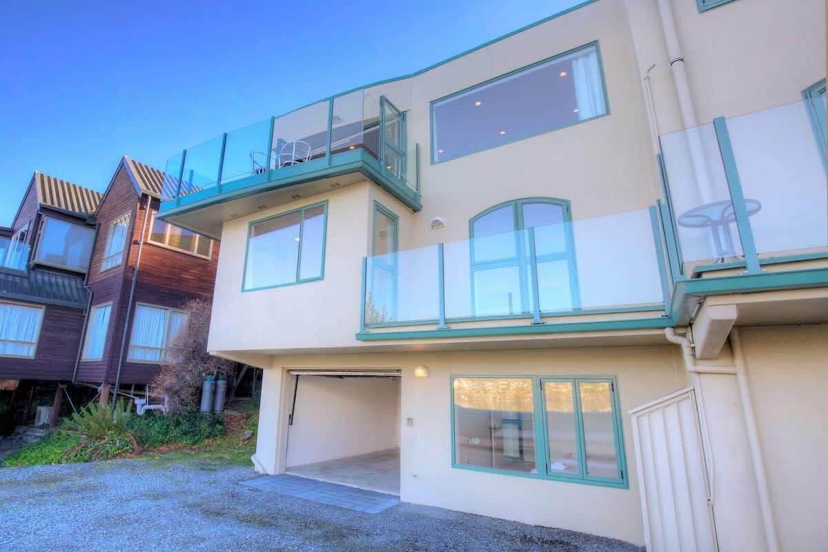 A multi-story residential building with a garage, large windows, and a balcony.
