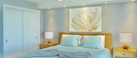 A bedroom with a bed, two bedside tables, a ceiling fan, and a wall art piece.