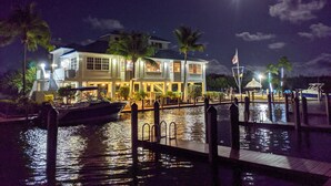A waterfront property with a dock, a boat, and a house with multiple levels and balconies.
