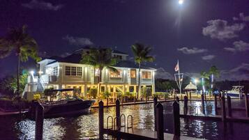 A waterfront property with a dock, a boat, and a house with multiple levels and balconies.