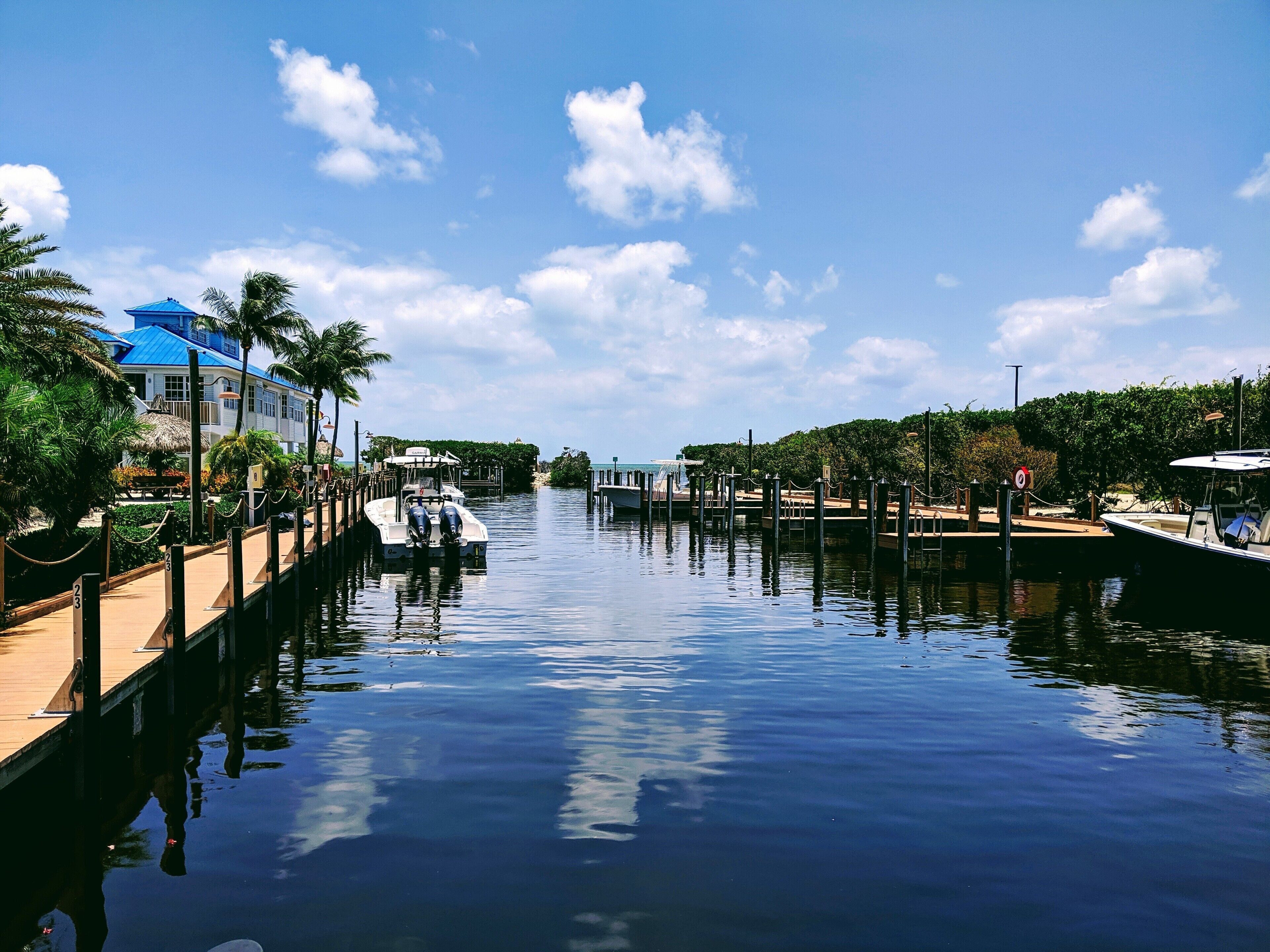 A canal with boats, a wooden dock, and a building with a blue roof.